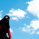 Personnage masqué noir et rouge sous un ciel bleu